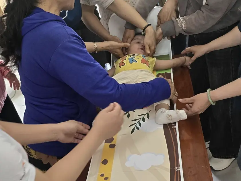 Health workers measuring an infant lying on the prototype board during the Vietnam field research.